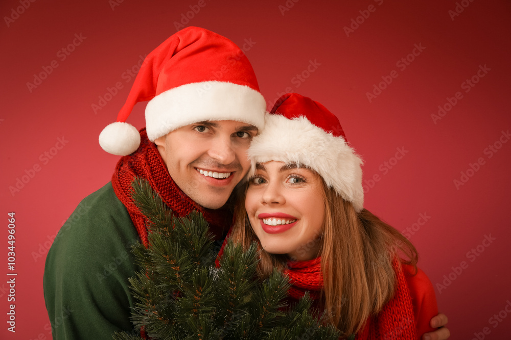Happy young couple with Christmas tree on red background Happy young couple with Christmas tree on red background