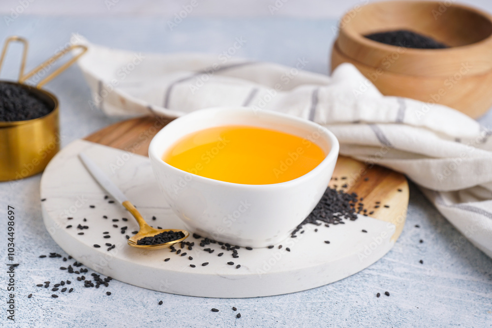 Bowl of oil with spoon and sesame seeds on white grunge background Bowl of oil with spoon and sesame seeds on white grunge background