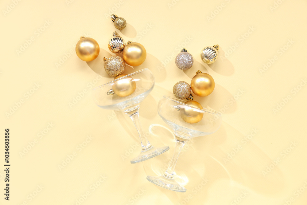 Champagne glasses with Christmas balls on yellow background Champagne glasses with Christmas balls on yellow background