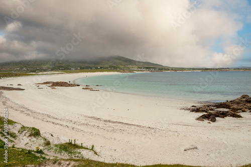 White sandy beach and ocean with blue turquoise color water. Dog bay, county Galway, Ireland. Popular tourist area with stunning Irish nature scenery. Cloudy sky. Travel and tourism. photo