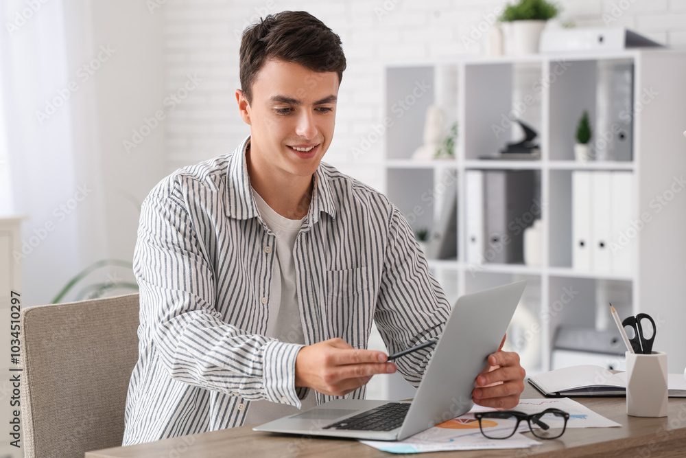 Male economist working with laptop at table in office Male economist working with laptop at table in office