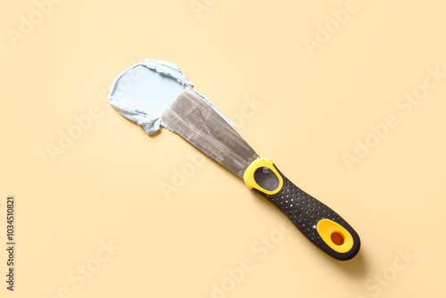 Knife with putty on beige background