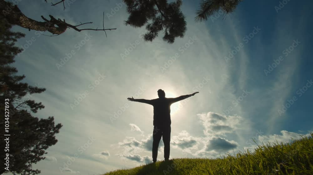 Man stands triumphantly under the sun, with hands up, essence of victory Man stands triumphantly under the sun, with hands up, essence of victory