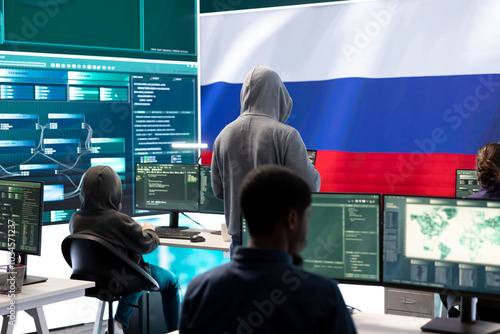 A hacker working in a governmental IT workspace with the USA flag running on big screen. Ensuring cybersecurity, cyber threat analysis and global surveillance to ensure cyber protection.