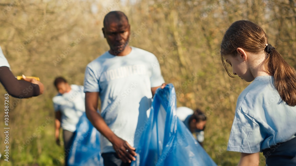 Diverse volunteers collecting garbage and junk from the forest area, fighting environmental pollution and conservation. Group of activists cleaning up the woods, recycling plastic waste. Camera A. Diverse volunteers collecting garbage and junk from the forest area, fighting environmental pollution and conservation. Group of activists cleaning up the woods, recycling plastic waste. Camera A.