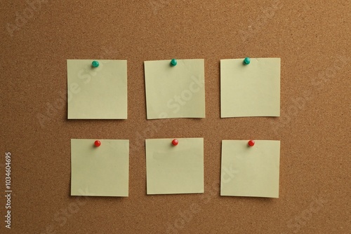 Beige paper notes pinned to cork board