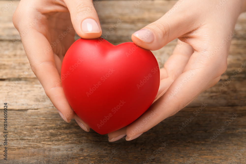 Woman with red decorative heart at wooden table, closeup Woman with red decorative heart at wooden table, closeup