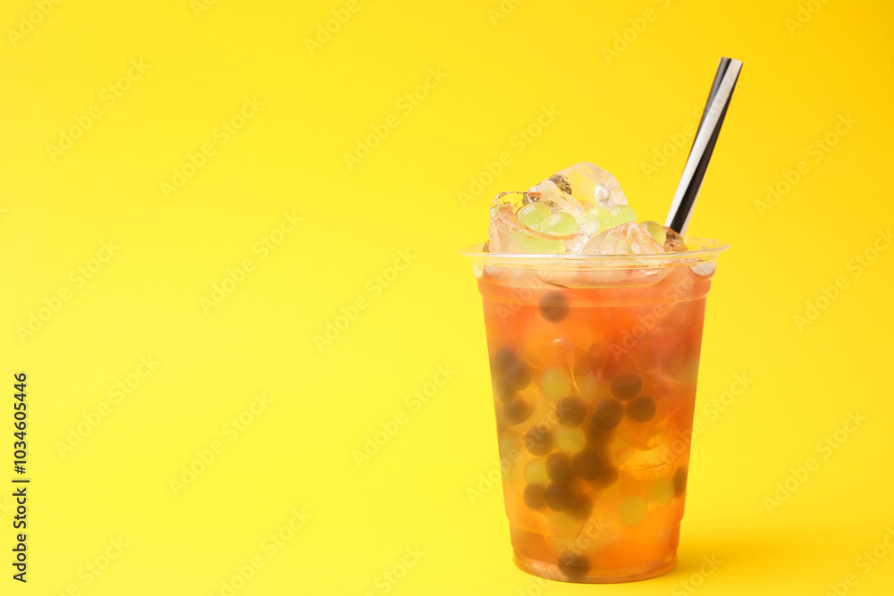 Tasty bubble tea in plastic cup on yellow background, space for text