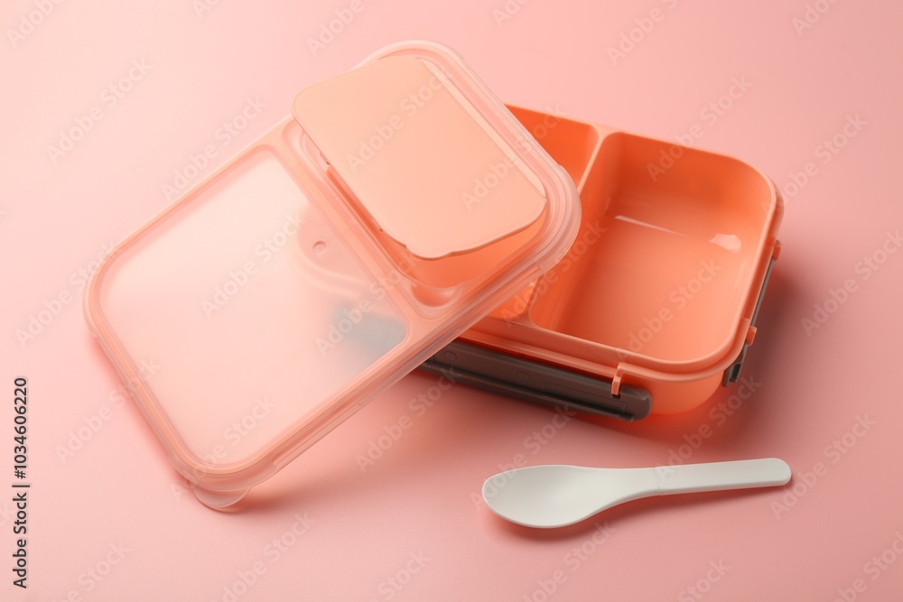 Empty lunch box and spoon on pink background Empty lunch box and spoon on pink background