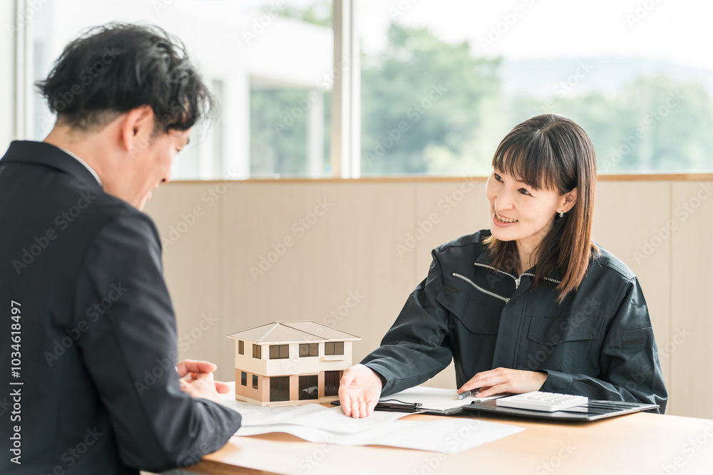 住宅模型や設計図を使って顧客にマイホームの説明・商談をするビジネスウーマン
住宅模型や設計図を使って顧客にマイホームの説明・商談をするビジネスウーマン