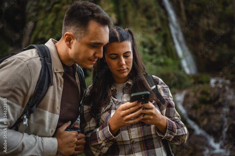 hiker couple backpackers stand in front waterfall and use cellphone hiker couple backpackers stand in front waterfall and use cellphone