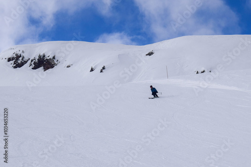 Young male skier in action skiing downhill in a European ski resort. Side view of skier descending in Les Menuires winter resort, France.