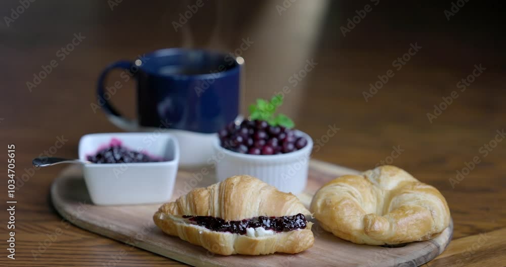 A plate of croissants and a cup of coffee sit on a wooden cutting board. The croissants are arranged in a way that they look like they are ready to be eaten with fresh wild berry jam. A plate of croissants and a cup of coffee sit on a wooden cutting board. The croissants are arranged in a way that they look like they are ready to be eaten with fresh wild berry jam.