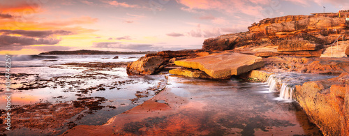 Sunrise across the ocean and broken  rockshelf