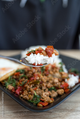 Rice and easil with Thai stir fried basil with minced pork on spoon. Close up