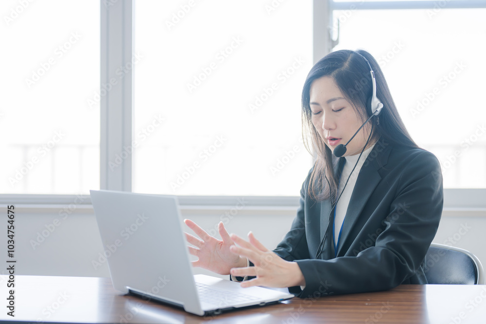 PCに向かって説明するインカムをした女性 PCに向かって説明するインカムをした女性