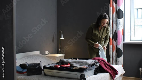 In a cozy bedroom, a young woman carefully packs her cosmetics and creams into an open suitcase, preparing for an getaway photo