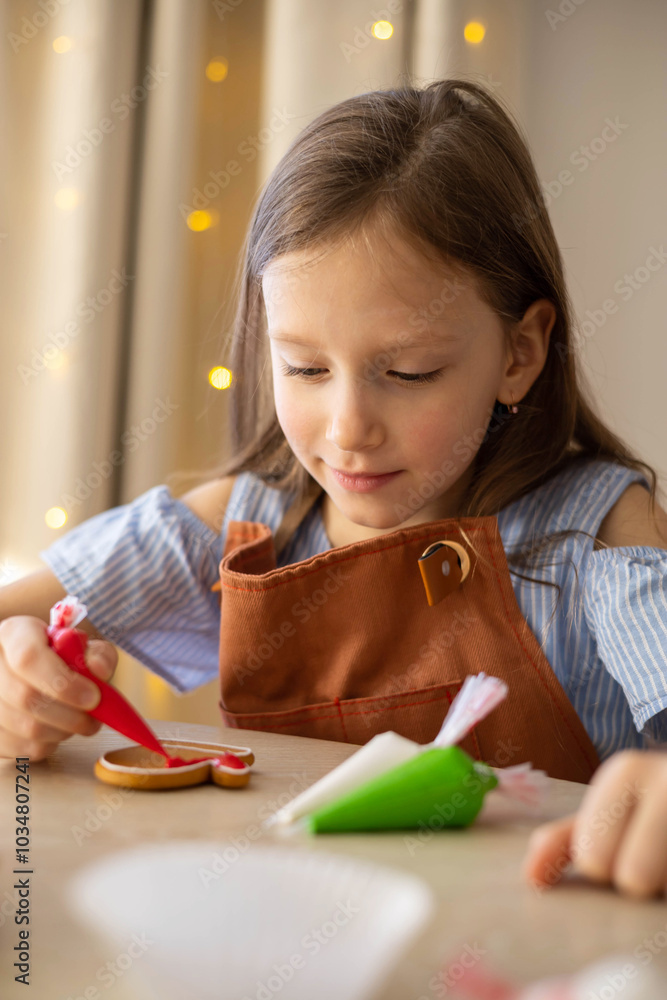 A little girl decorates a Christmas gingerbread mitten with icing. Concept Christmas A little girl decorates a Christmas gingerbread mitten with icing. Concept Christmas