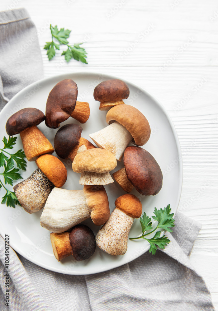 A variety of fresh mushrooms displayed on a plate surrounded by green herbs on a simple wooden surface A variety of fresh mushrooms displayed on a plate surrounded by green herbs on a simple wooden surface
