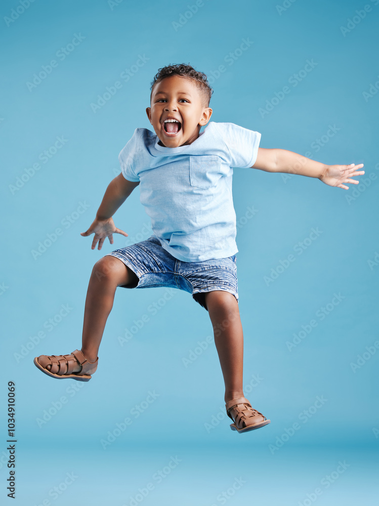 Studio, kid and boy with energy for jump, playful and freedom with celebration for back to school. Male person, child and scream with game for kindergarten, childhood and flying by blue background Studio, kid and boy with energy for jump, playful and freedom with celebration for back to school. Male person, child and scream with game for kindergarten, childhood and flying by blue background