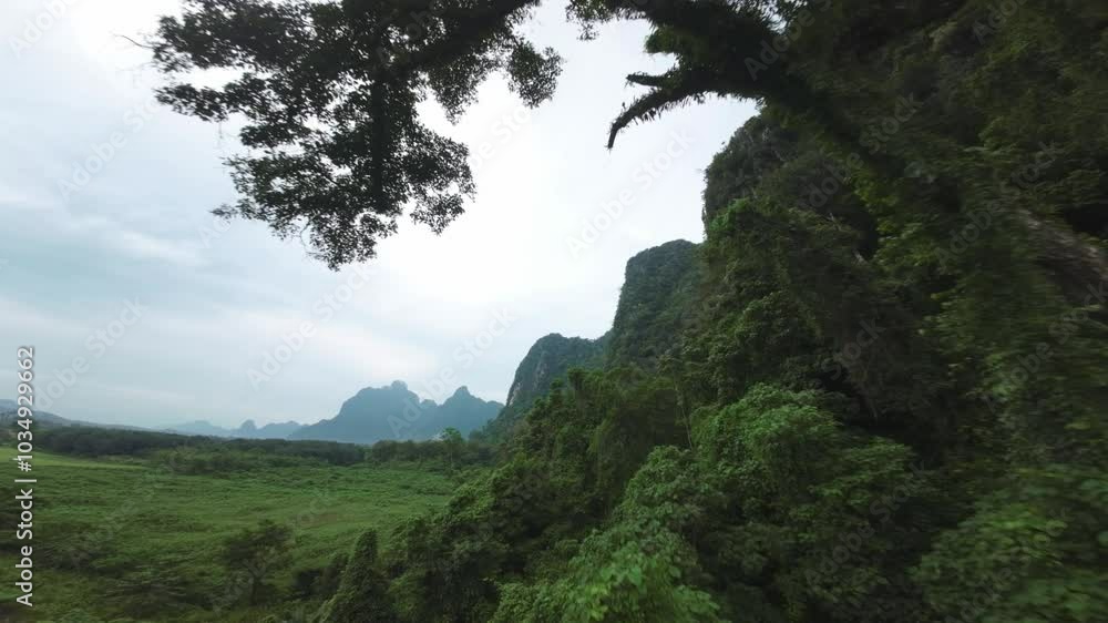Aerial view over the tranquil waters and green landscape of Blue Lagoon, Laos, surrounded by high cliffs, rise between overhanging trees Aerial view over the tranquil waters and green landscape of Blue Lagoon, Laos, surrounded by high cliffs, rise between overhanging trees
