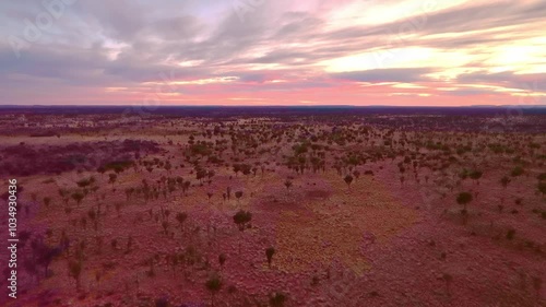 Flying over the vast Australian red desert landscape during fiery sunrise photo