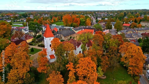 Talsu church in latvia surrounded by vibrant autumn trees and scenic townscape, aerial view photo