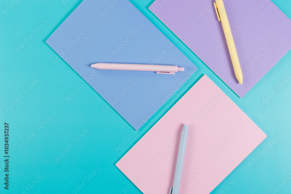 Top view of pink, purple and blue notebooks on blue background. Pink, yellow and blue pens, school, office wallpaper. Flat lay, copy space. Top view of pink, purple and blue notebooks on blue background. Pink, yellow and blue pens, school, office wallpaper. Flat lay, copy space.