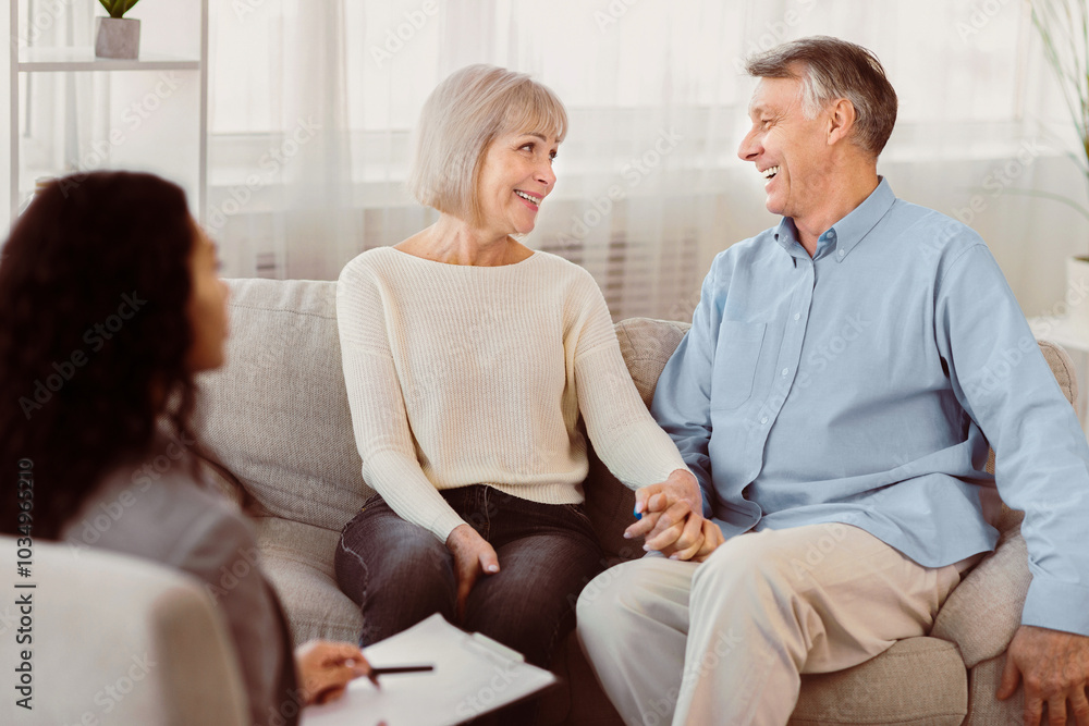 Love And Family Concept. Happy mature couple holding hands, looking at each other at psychologist office after session Love And Family Concept. Happy mature couple holding hands, looking at each other at psychologist office after session