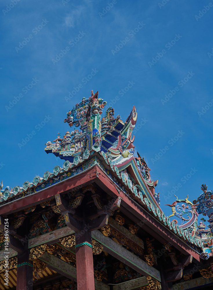 Naklejka premium Ancient Chinese-style roof details in George town, Penang, stand out against blue sky.