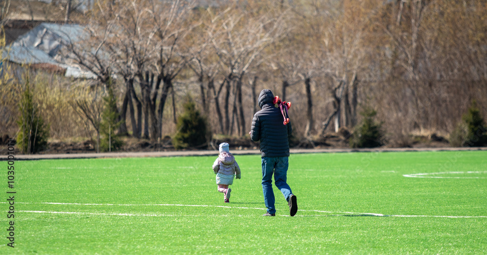 Petropavlovsk, Kazakhstan - May 4, 2021: Child with parents on a green soccer field. Petropavlovsk, Kazakhstan - May 4, 2021: Child with parents on a green soccer field.