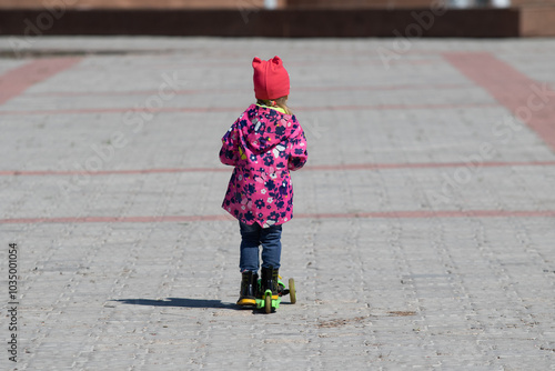 Petropavlovsk, Kazakhstan - May 4, 2021: The child is riding a scooter on paving stones. photo