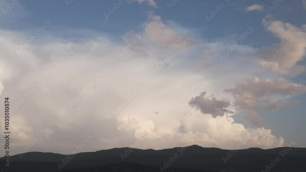 Spectacular drone filming of a large Cumulonimbus created behind a line of mountains and with a blue sky background, it is evolving and we appreciate its great width, Spectacular drone filming of a large Cumulonimbus created behind a line of mountains and with a blue sky background, it is evolving and we appreciate its great width,
