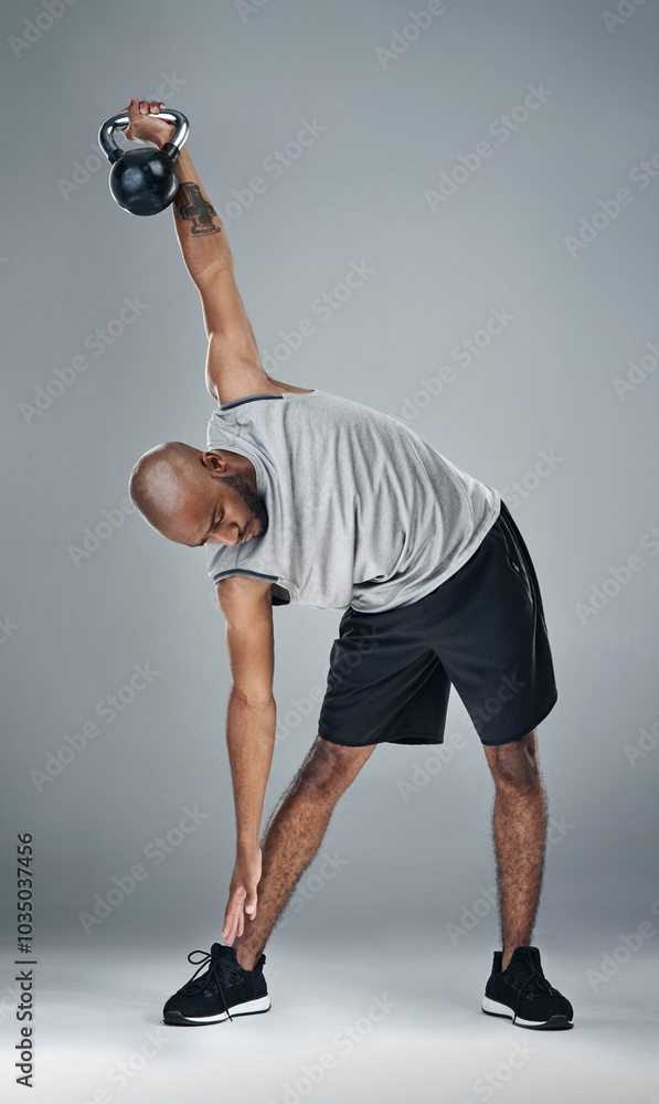 Stretching, black man and kettle bell in studio for fitness, workout and exercise on gray background. Male person, serious and trainer with sportswear with training for health, wellbeing or self care Stretching, black man and kettle bell in studio for fitness, workout and exercise on gray background. Male person, serious and trainer with sportswear with training for health, wellbeing or self care