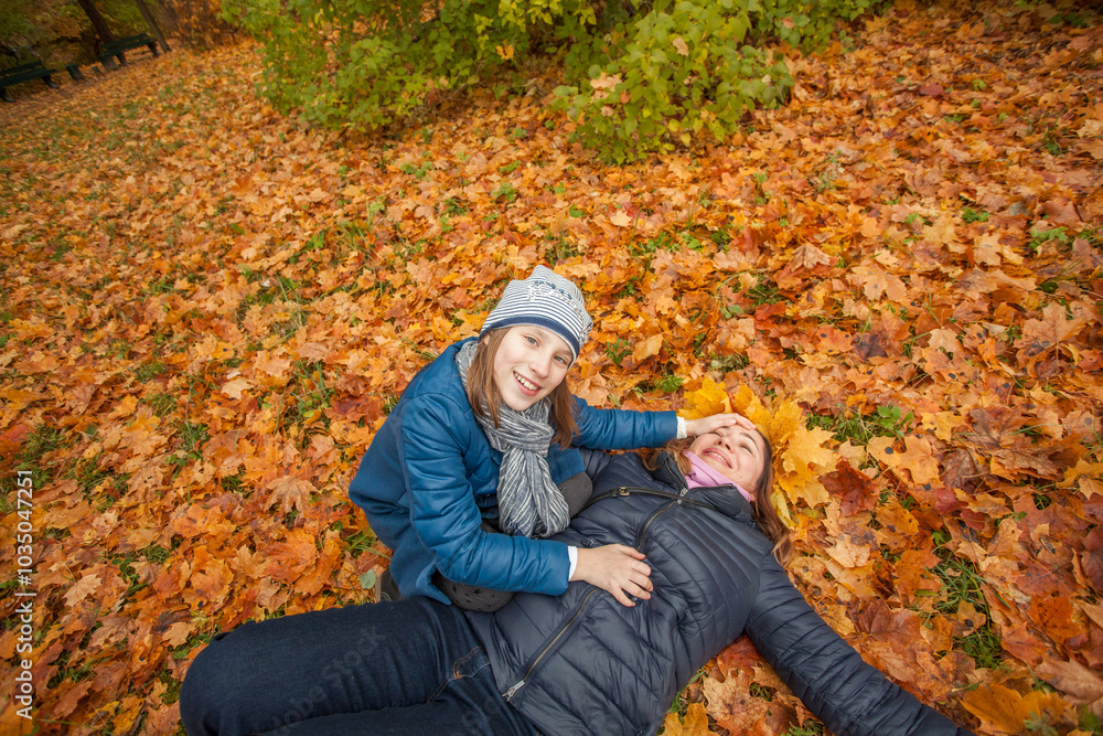 Pretty mother with daughter in autumn day on yellow fall leaves background Pretty mother with daughter in autumn day on yellow fall leaves background