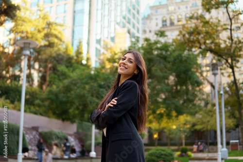 Portrait of beautiful businesswoman standing with arms crossed outdoors in a vibrant urban setting