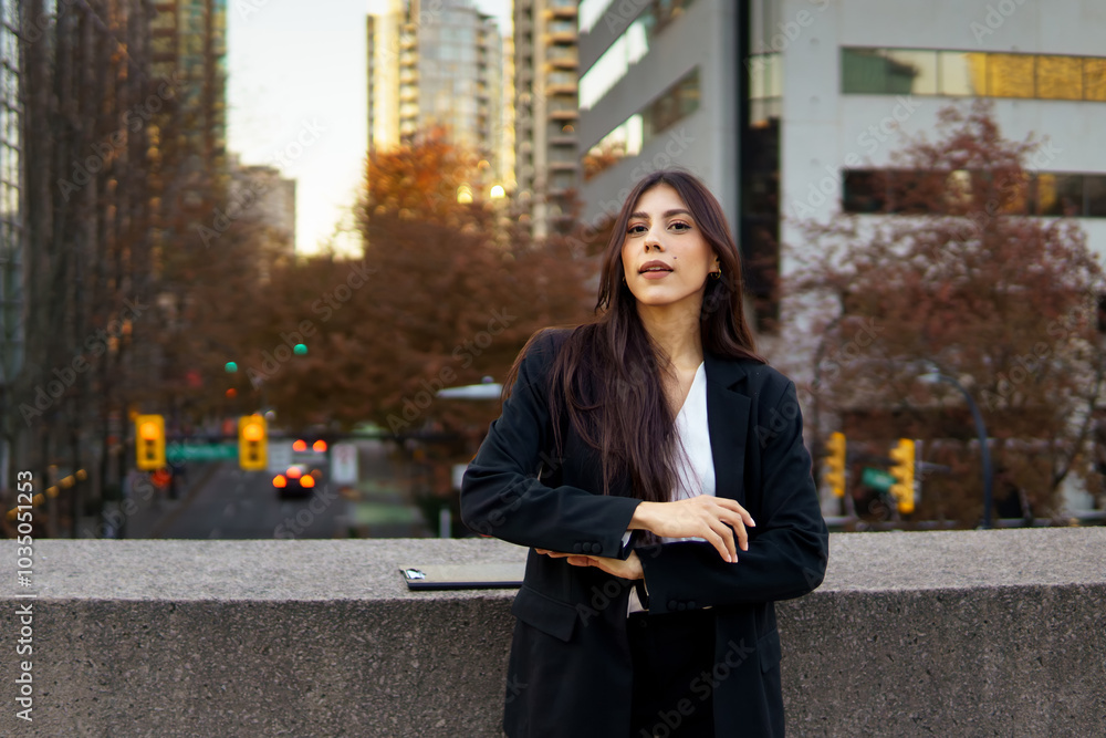 Confident hispanic businesswoman standing in front of a modern building with autumn foliage Confident hispanic businesswoman standing in front of a modern building with autumn foliage