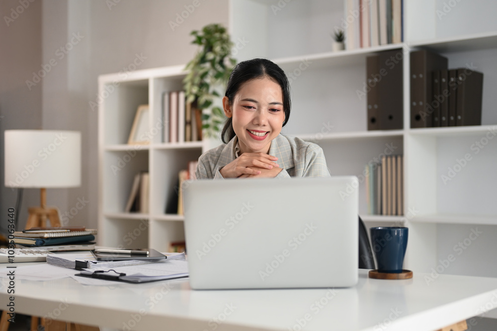 Charming businesswoman watching online webinar on laptop in office Charming businesswoman watching online webinar on laptop in office