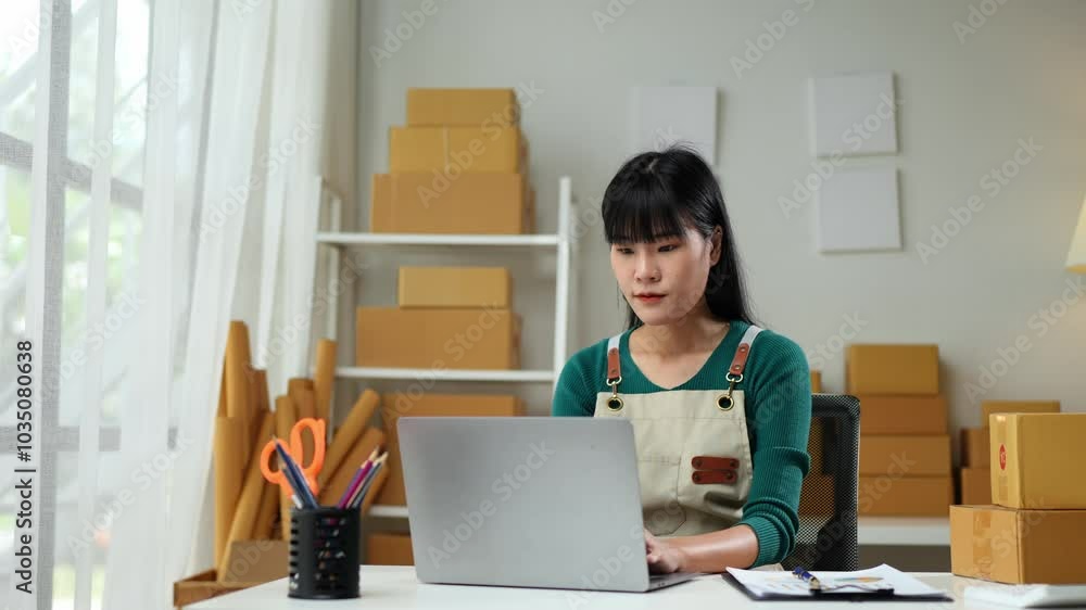 Independent business woman SME uses laptop computer, mobile phone to check customer orders. Checking parcel boxes delivered online at home. Entrepreneur. Freelance. Startup business idea. Independent business woman SME uses laptop computer, mobile phone to check customer orders. Checking parcel boxes delivered online at home. Entrepreneur. Freelance. Startup business idea.