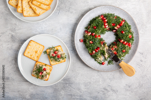 Tuna pate decorated with dill and pomegranate seeds in shape of wreath served with crackers.