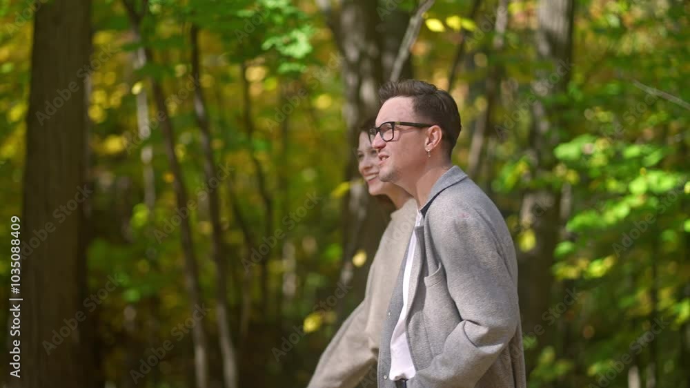 A loving couple strolls hand in hand through a vibrant forest, showcasing natures beauty and intimacy A loving couple strolls hand in hand through a vibrant forest, showcasing natures beauty and intimacy