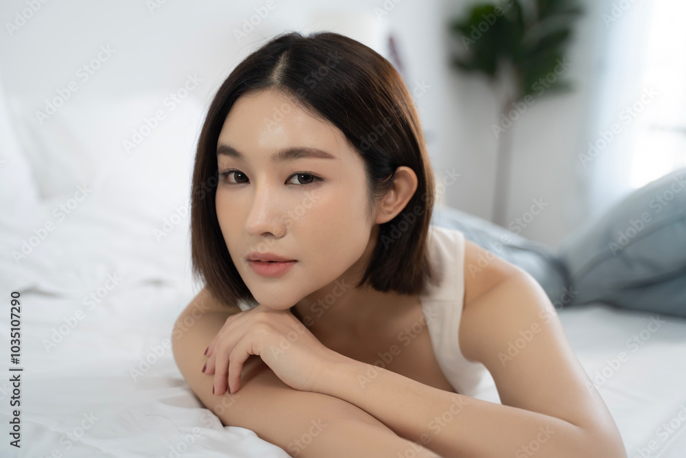 A serene close-up portrait of an Asian woman resting on a bed in a modern home, showing a peaceful expression and relaxed posture, ideal for themes of comfort, self-care, and everyday beauty. A serene close-up portrait of an Asian woman resting on a bed in a modern home, showing a peaceful expression and relaxed posture, ideal for themes of comfort, self-care, and everyday beauty.