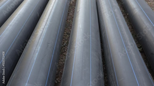 Long plastic black pipes of large diameter lie on the ground on the street. View from above. Close-up. Sewer pipes, water pipes, heating pipes. High quality 4k footage