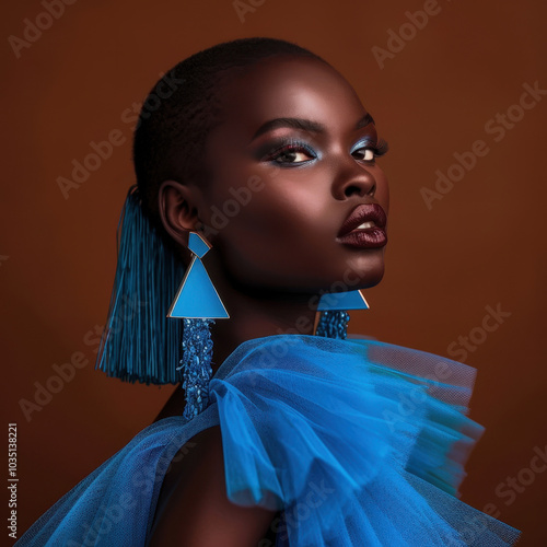 Portrait of a vibrant individual wearing bold geometric earrings and a striking blue outfit, showcasing modern fashion style photo