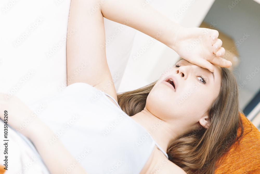 Young woman feeling sick and having fever on sofa at home Young woman feeling sick and having fever on sofa at home