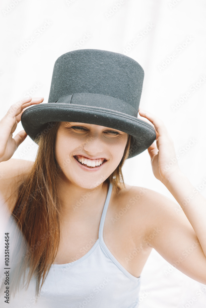 Young woman wearing a black top hat smiling and posing Young woman wearing a black top hat smiling and posing