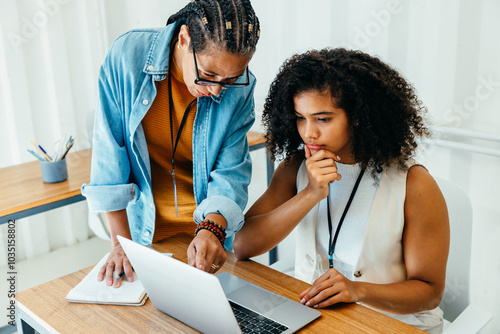Manager providing training to focused intern in a business setting