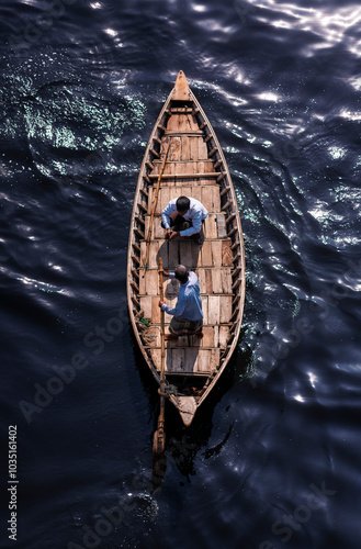 Aerial view of water taxi crossing over the clear river Buriganga with traditional wooden boats and people, Keraniganj, Bangladesh. photo