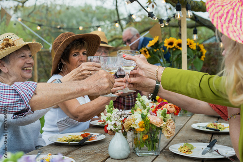 Konstfotografi Cheerful senior friends toasting at outdoor garden party