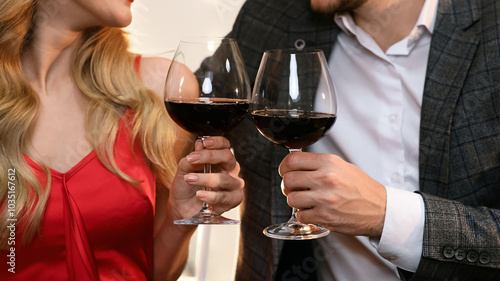 Cheers. Closeup of glasses with red wine in hands of happy couple on date in restaurant, romantic pair celebrating Valentine's day together, crop